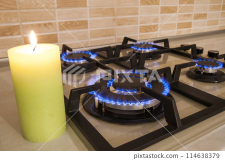 Closeup shot of blue fire from domestic kitchen stove. Gas cooker with burning flames propane gas and candle. Old and new concept Closeup shot of blue fire from domestic kitchen stove. Gas cooker with burning flames propane gas and candle. Old and new concept 114638379
