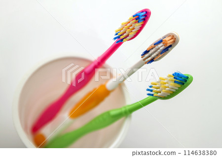 Close up shot of set of multicolored toothbrushes in glass on clean toilet on white background, concept dental. 114638380