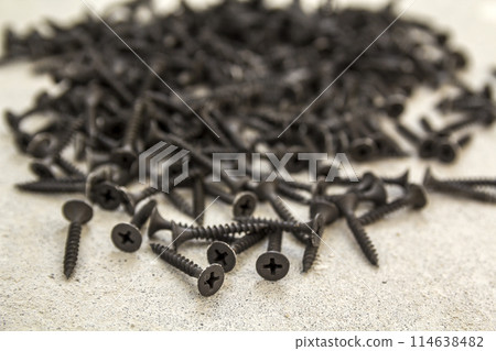 Close-up image of many small black screws on concrete background Close-up image of many small black screws on concrete background 114638482