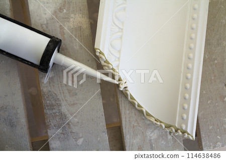 Close-up detail of decoration molding with glue adhesive before installation in interior renovation. Close-up detail of decoration molding with glue adhesive before installation in interior renovation. 114638486