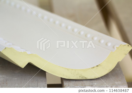 Close-up detail of decoration molding with glue adhesive before installation in interior renovation. Close-up detail of decoration molding with glue adhesive before installation in interior renovation. 114638487