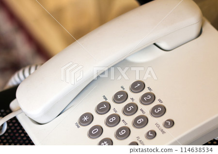 Close up of telephone device at office desk, communication technology concept Close up of telephone device at office desk, communication technology concept 114638534