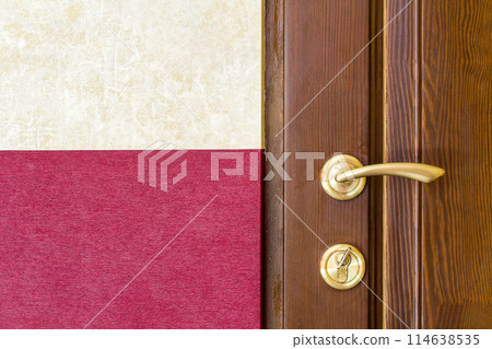 Modern, contemporary satin metal handle and a key in lock on a wooden door close-up. Modern, contemporary satin metal handle and a key in lock on a wooden door close-up. 114638535