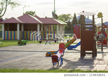 Beautiful new modern playground in kindergarten with soft pavement, bright new multicolored alcoves, swings, slides, benches, roundabout and sandbox. Perfect place for children activities outdoors. 114638641