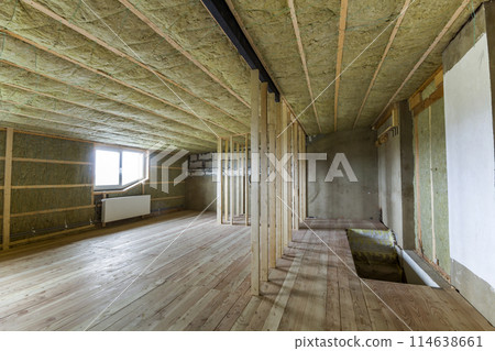 Construction and renovation of big light spacious empty room with oak floor, walls and ceiling insulated with rock wool, heating radiators under low attic windows and wooden frame for future walls. 114638661
