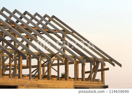 Close-up detail of new attic wooden roof frame against clear sky. Professional building, roofing, construction and renovation concept. Investment in real estate property and ecological home concept. 114638690