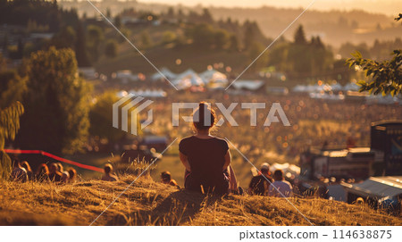 festival goer figure perched atop a hill overlooking a one of the largest summer music festival 114638875