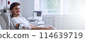 Banner Young Smiling Man Donating Blood In Hospital. Copy Space For Text. World Blood Donor Day, June 14. Horizontal Design, Medical Dropper, Device. Ai Generated. Mockup. 114639719