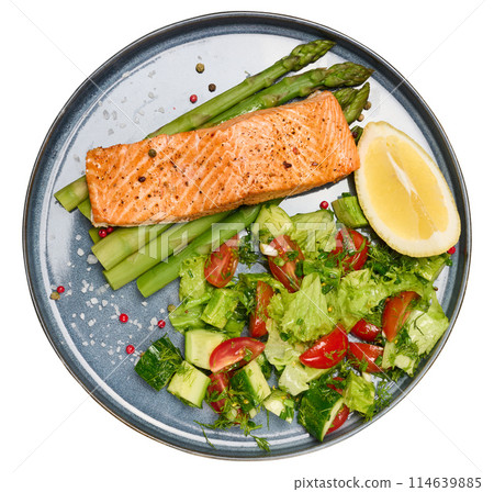 Healthy lunch with grilled trout with asparagus and fresh tomato and cucumber salad, a row of lemon slice. 114639885