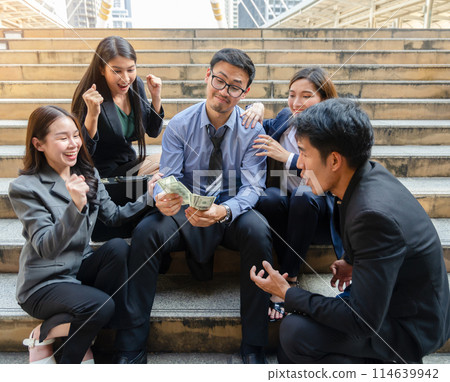 Happiness business people receiving money dollar banknotes after job done and success business deals. A man with eyeglasses holding dollar banknotes in hands and sitting together with excited business 114639942