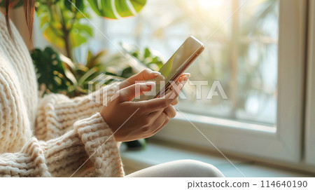 A woman's hand operating a smartphone in a room 114640190