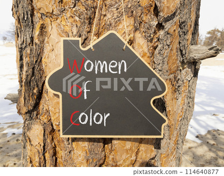 WOC women of color symbol. Concept words WOC women of color on beautiful yellow blackboard. Beautiful tree wooden background. Business WOC women of color social issues concept. Copy space. 114640877