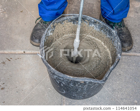 Construction worker mixing mortar in a bucket Construction worker mixing mortar in a bucket 114641054