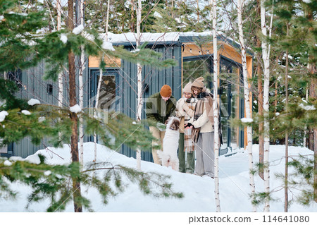 Wide shot of modern Caucasian family of three with pet enjoying spending winter day outdoors, copy space 114641080
