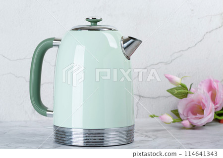 A green electric kettle and roses on the kitchen table. 114641343