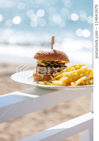 Lunch on the beach. Juicy hot cheeseburger with fries 114641678