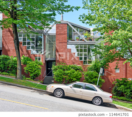 Residential townhouses on the street going uphill with a car parked in front 114641701