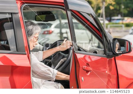 Senior driver Asian woman getting in and out of the driver's seat of a car Senior driver Asian woman getting in and out of the driver's seat of a car 114645523