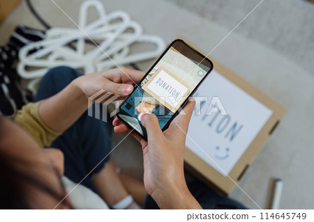Asian woman use mobile phone to take photo of donation box to encourage friend on social media to donate 114645749