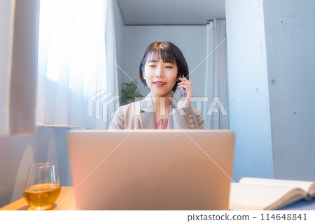 Woman studying at home/Woman working remotely/Woman making a phone call on her smartphone Woman studying at home/Woman working remotely/Woman making a phone call on her smartphone 114648841