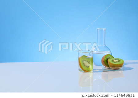 Kiwi and laboratory theme photograph with a few instruments in lab containing kiwi featured on the right side of white table, vacant left side space, over blue texture. Front view, copy space 114649631