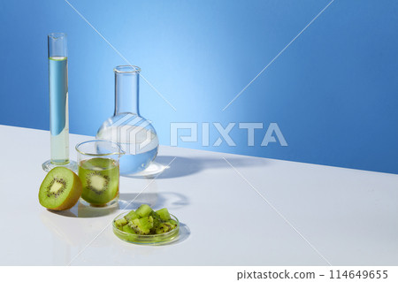 White countertop containing some equipments in laboratory and fresh kiwi on the left side, the other side is vacant space for showing product or adding design elements, over blue background White countertop containing some equipments in laboratory and fresh kiwi on the left side, the other side is vacant space for showing product or adding design elements, over blue background 114649655