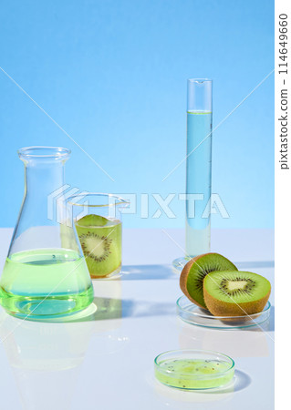 Creative photo for promotion was shot from front, the white flat against blue background with gradient effect, erlenmeyer flask and measuring cylinder with light green fluid and fresh kiwi Creative photo for promotion was shot from front, the white flat against blue background with gradient effect, erlenmeyer flask and measuring cylinder with light green fluid and fresh kiwi 114649660