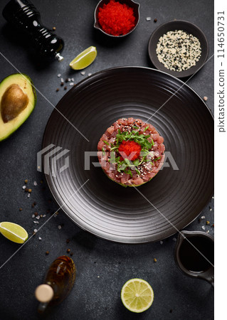 Tuna and avocado tartare on a dark ceramic plate Tuna and avocado tartare on a dark ceramic plate 114650731
