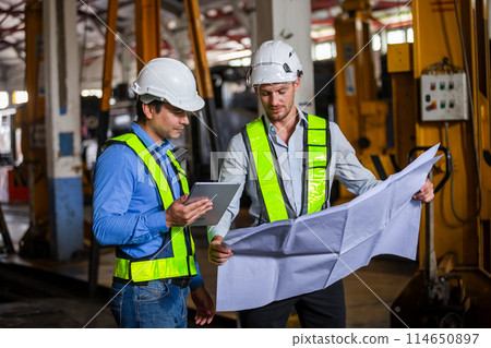 Railway technician engineer wearing safety uniform and safety helmet holding tablet and blueprint. 114650897
