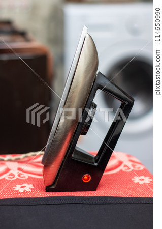 A black iron rests on a red table cloth in a automotive themed setting A black iron rests on a red table cloth in a automotive themed setting 114650990