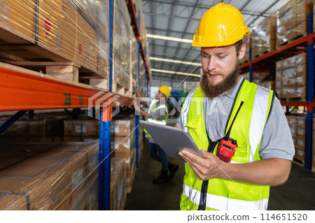 Male holding tablet quality control standing at machine of factory warehouse. 114651520