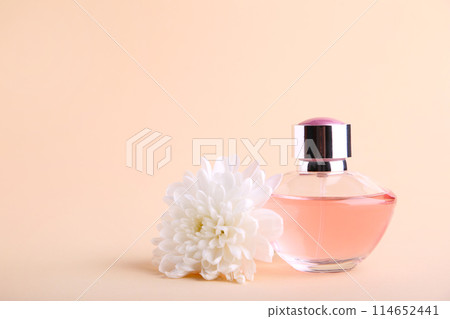 Bottle of perfume with flower on beige background Bottle of perfume with flower on beige background 114652441