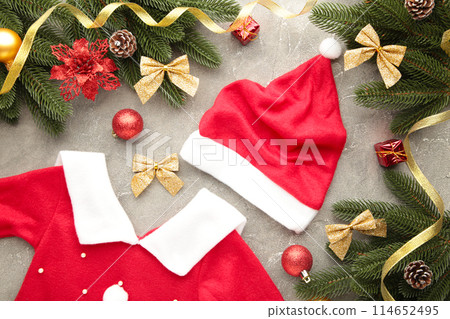 Santa Claus red hat and dress with decoration on grey background. Christmas decoration. Santa Claus red hat and dress with decoration on grey background. Christmas decoration. 114652495