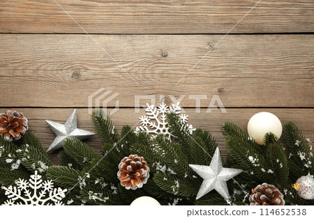 Fir tree branches with silver christmas decoration on a grey background Fir tree branches with silver christmas decoration on a grey background 114652538