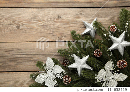 Fir tree branches with silver christmas decoration on a grey background Fir tree branches with silver christmas decoration on a grey background 114652539
