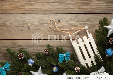 Christmas toy sledge with fir-tree branch on a grey wooden background. Christmas toy sledge with fir-tree branch on a grey wooden background. 114652540