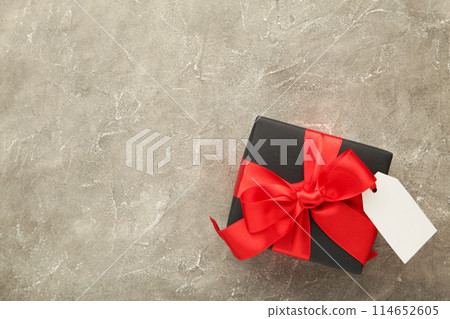 Black gift box with sale tag on grey concrete background Black gift box with sale tag on grey concrete background 114652605