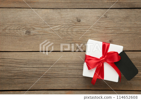 White gift box with red ribbon with sale tag isolated on grey wooden background 114652608