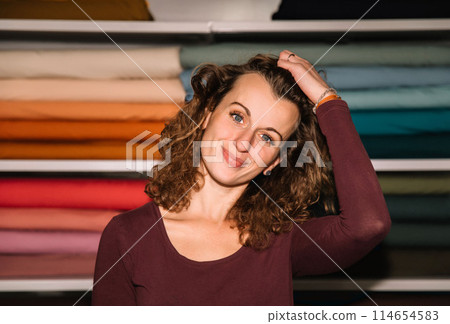 Stylish woman with curly hair in craft textile store, design concept Stylish woman with curly hair in craft textile store, design concept 114654583