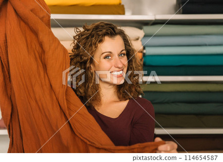 Stylish woman with curly hair in craft textile store, design concept 114654587