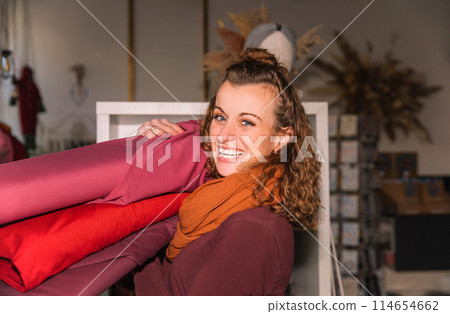 Stylish woman with curly hair in craft textile store, design concept 114654662