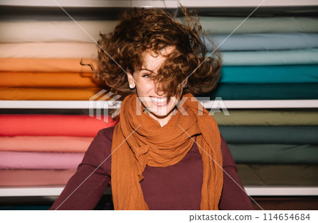 Stylish woman with curly hair in craft textile store, design concept 114654684