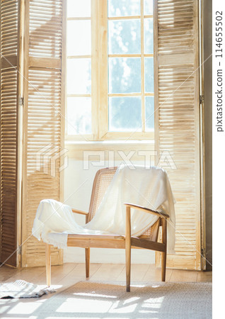 Wooden armchair with plaid against windows with shutters , room composition and sunlight Wooden armchair with plaid against windows with shutters , room composition and sunlight 114655502