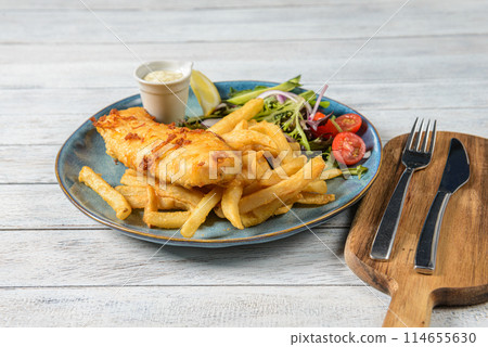 Fish and Chips is a classic British dish featuring battered and deep-fried fish, usually cod or haddock, served with crispy potato fries. It's known for its crunchy texture and savory flavor Fish and Chips is a classic British dish featuring battered and deep-fried fish, usually cod or haddock, served with crispy potato fries. It's known for its crunchy texture and savory flavor 114655630