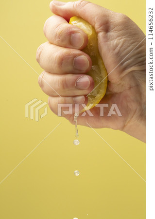 Squeezing lemon on yellow background Squeezing lemon on yellow background 114656232