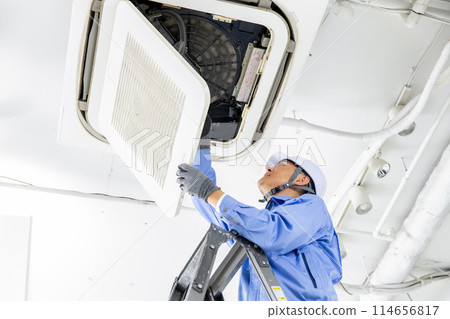 Man in work clothes inspecting air conditioner 114656817