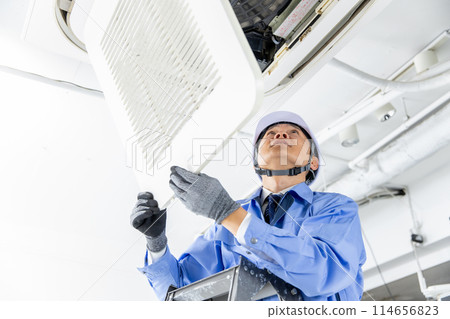 Man in work clothes inspecting air conditioner 114656823