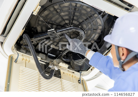 Man in work clothes inspecting air conditioner Man in work clothes inspecting air conditioner 114656827