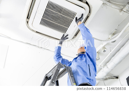Man in work clothes inspecting air conditioner 114656838