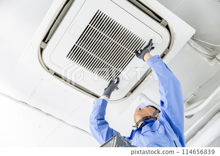 Man in work clothes inspecting air conditioner Man in work clothes inspecting air conditioner 114656839